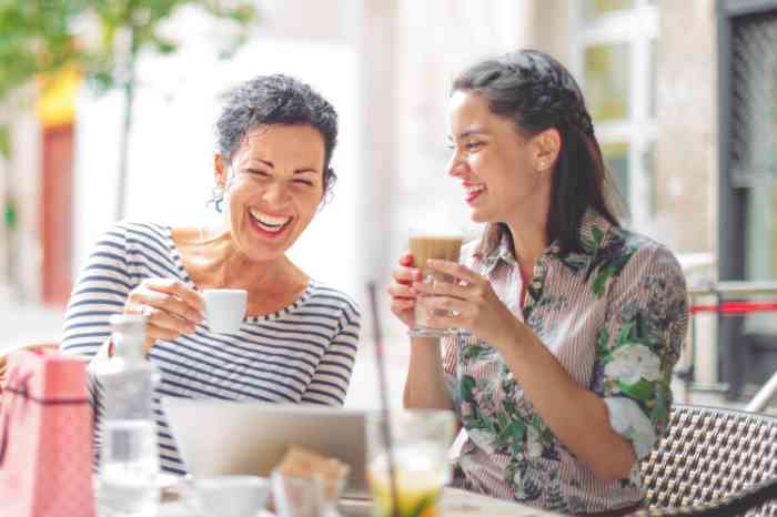 Adult mother and daughter laughing over a cup of tea