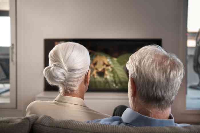 Elderly couple watching TV using TV streamer to hearing aids