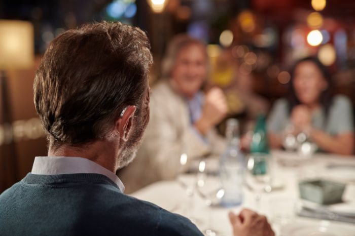man wearing hearing aids at dinner table