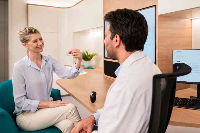 Woman putting on hearing aid