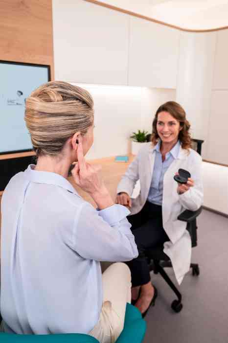 A woman connecting a hearing aid to a mobile device