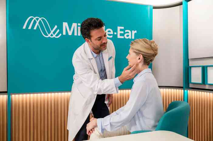 Hearing Care Specialist showing off ITE hearing aid to patients