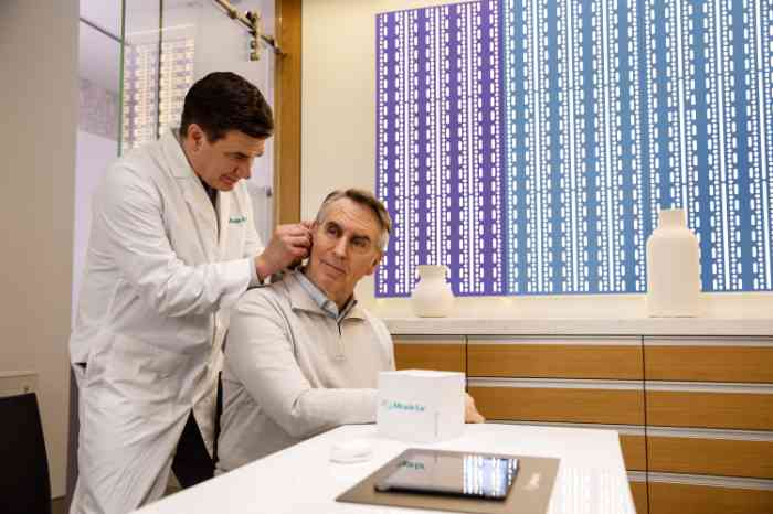 A specialist fitting a hearing aid for a customer