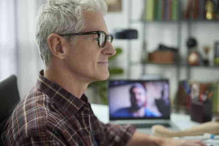 Man with glasses viewing his computer screen