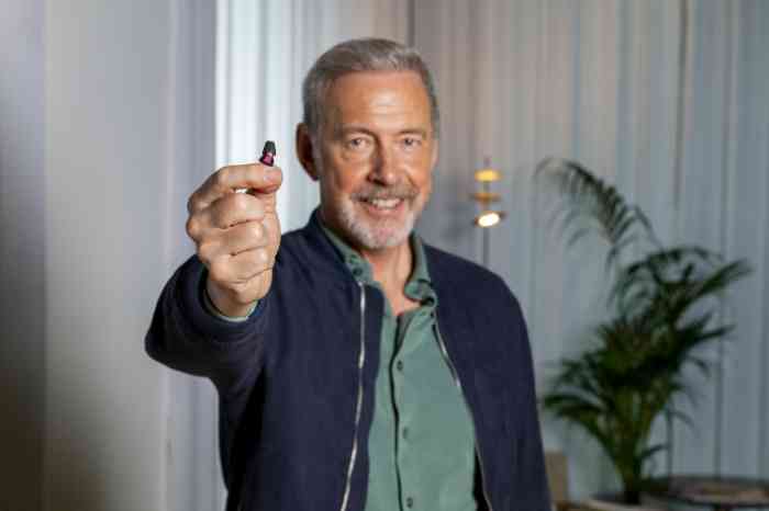 Smiling man holding hearing aid