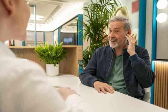 Man talking about hearing aids with hand on ear 