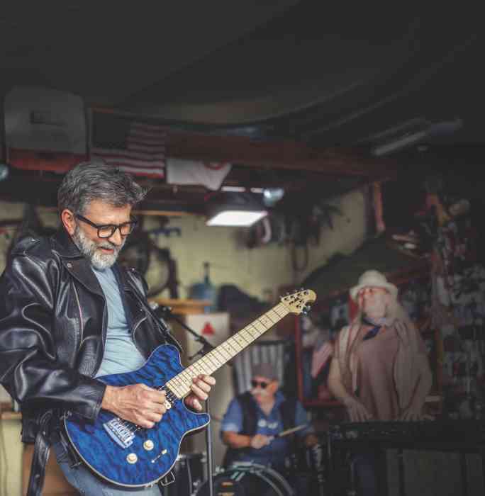 Man happily jamming on his guitar in his garage