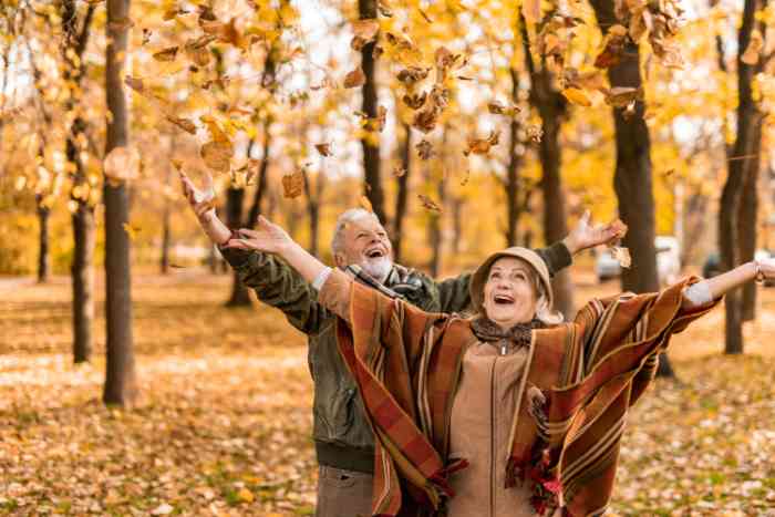 happy couple enjoying fall joyfully throwing leaves in the air
