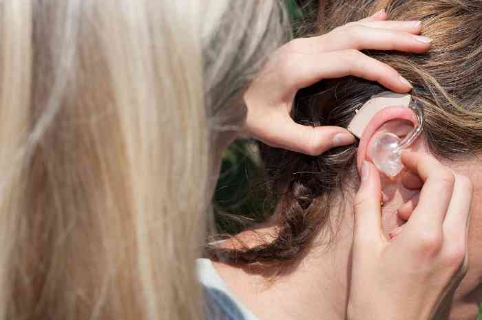 Specialist testing a hearing aid on a woman.
