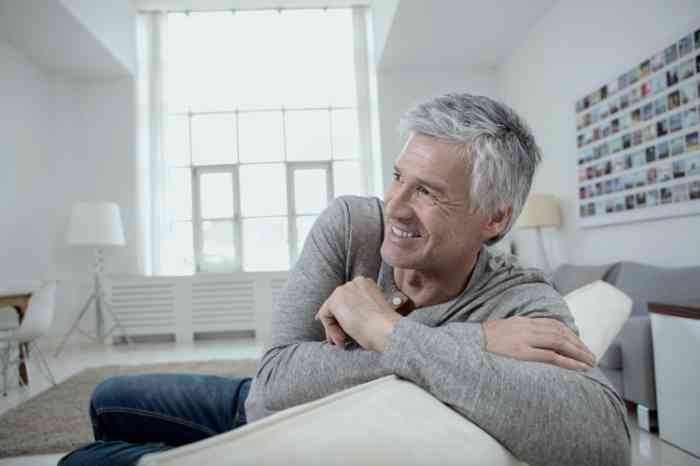 An elderly man smiling on his white sofa