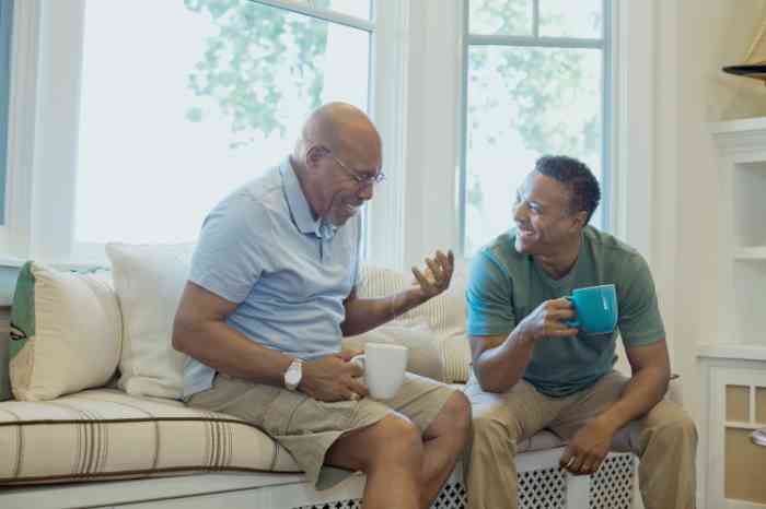 Friends laughing on a sofa with two cups of tea