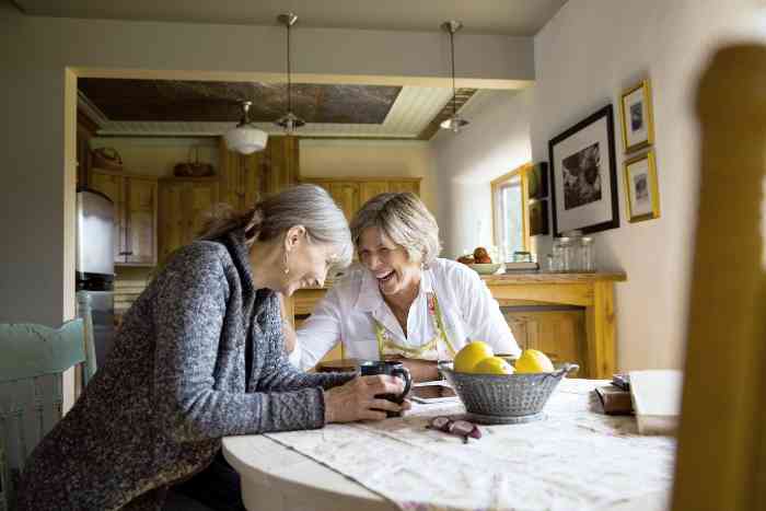 Laughing senior women drinking coffee at dining table
