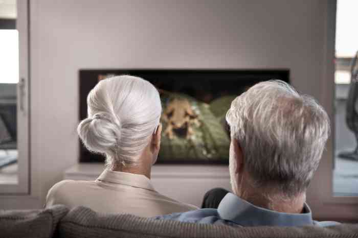 Women and man watching tv and wearing hearing aids