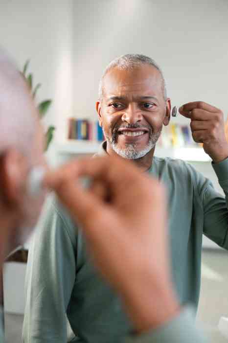Smiling man holding hearing aid