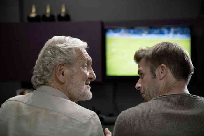 Grandfather and grandson watching a football match on tv