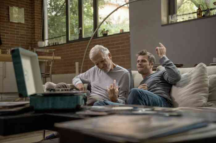 Grandfather and grandson playing air guitar on their sofa