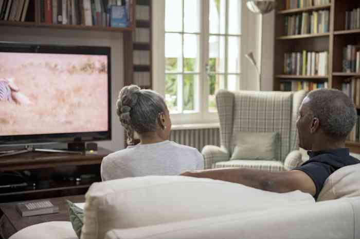 Couple with hearing aids watching TV on a sofa