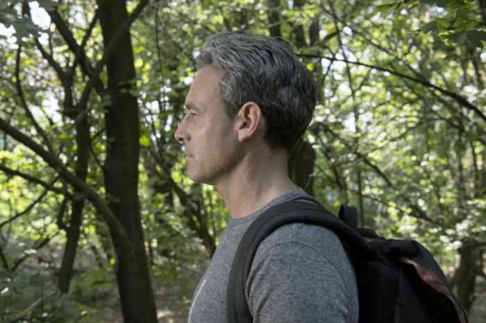 Profile of a man with invisible hearing aid with a backpack on his shoulders