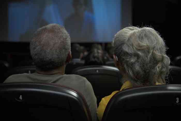 Elderly couple with BTE hearing aids watching a movie at the cinema