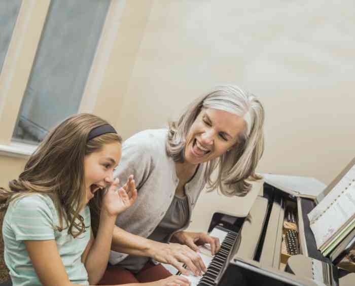 Elderly woman playing a piano with her granddaughter