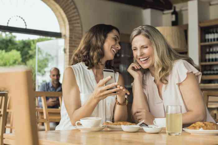 Two friends laughing looking at a smartphone