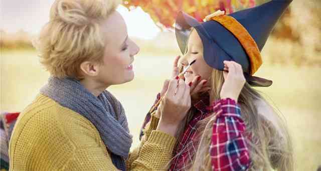 A woman helping the little daughter with Halloween make-up