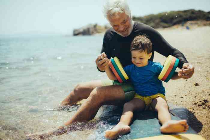 Grandfather playing with his grandson on a beach near the sea
