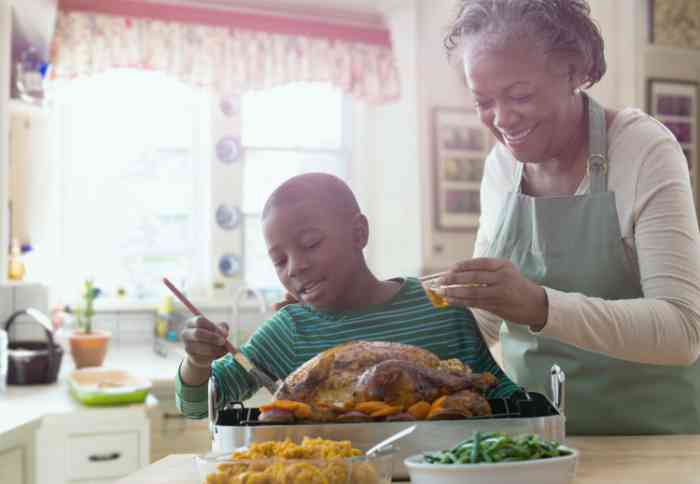 Elderly woman and her grandson prepare a roast chicken in their kitchen