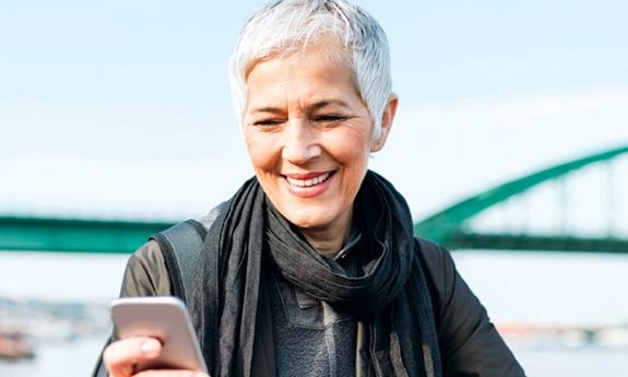 Woman outside on her phone with coffee