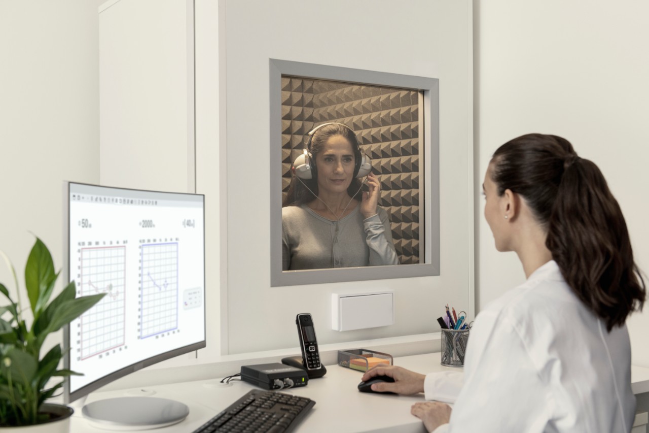 Miracle-Ear hearing aid specialist shaking hands with two customers in a Miracle-Ear center