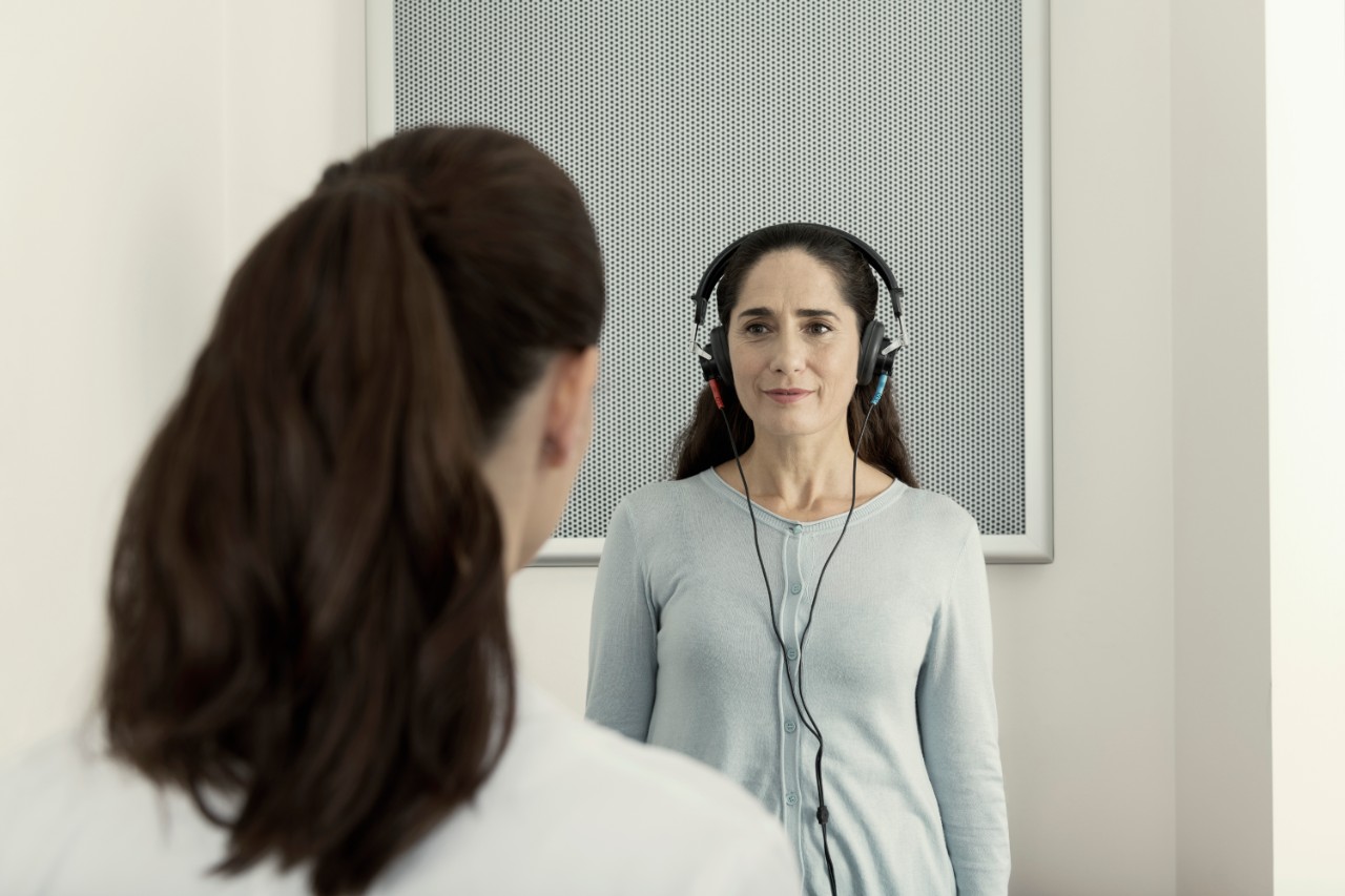 Miracle-Ear hearing care specialist showing a hearing aid in the palm of her hand