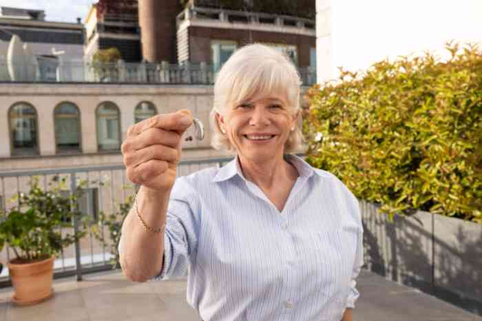 patient testimonial woman with yellow sweater holding hearing aid