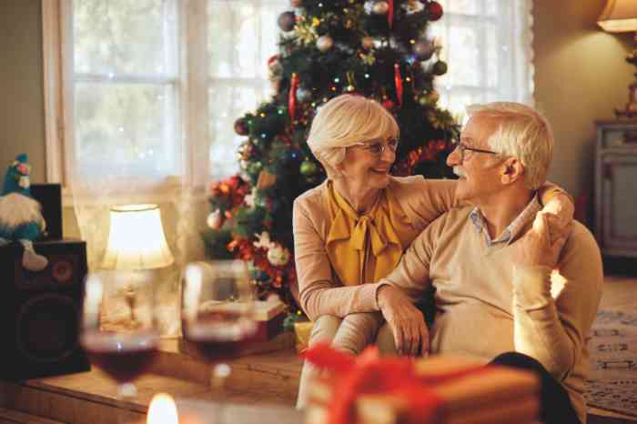 Old couple smiling with a Christmas tree on the background