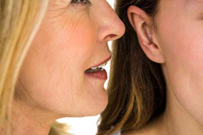 Woman whispering something into another woman's ear